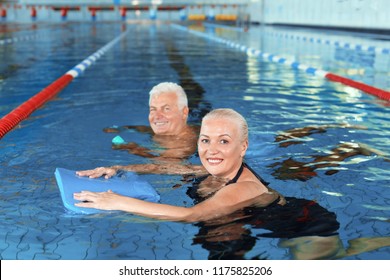 Sportive senior couple doing exercises in indoor swimming pool - Powered by Shutterstock