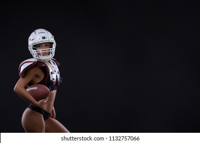 Sportive serious woman in helmet of rugby player holding ball in stuio on dark background. . Copy space