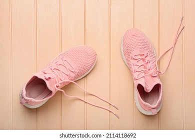 Sportive Shoes With Untied Shoe Laces On Color Wooden Background