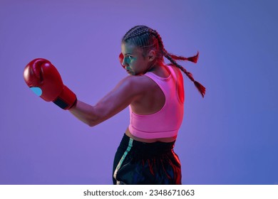 Muchacha adolescente deportiva, atleta de MMA con guantes de boxeo y uniforme, entrenando con fondo morado en luces de neón. Concepto de artes marciales mixtas, deporte, hobby, competencia, atletismo, fuerza y