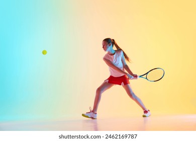 Sportive teen girl, tennis athlete training skills of hitting ball from opponent in neon light against blue-yellow background. Concept of individual kind of sports, fashion, tournament, action. Ad - Powered by Shutterstock