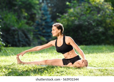 Sportive Woman With Brown Hair Wearing Black Top And Shorts Doing Yoga Position In Park, Healthy Lifestyle, Portrait, Maha Mudra Asana.