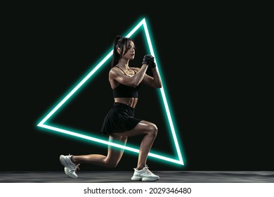 Sportive Woman, Fitness Coach Training Isolated On Black Background With Luminescent Triangle. Abstract Desing, Concept Of Active Lifestyle, Beauty, Motion In Sport. Squats, Lunges. Copy Space For Ad