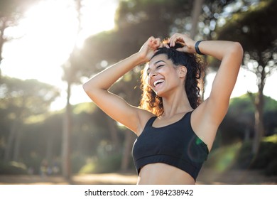 Sportive woman running in a forest - Beautiful woman with curly hair, wearing sportswear - Beautiful sportive woman, exercising in a forest