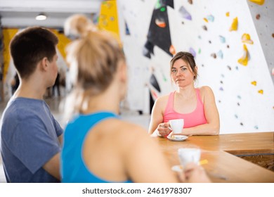 Sportive woman standing at bar counter in bouldering club and having conversation with friends during coffee break. - Powered by Shutterstock