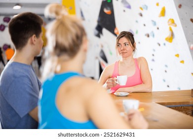 Sportive woman standing at bar counter in bouldering club and having conversation with friends during coffee break. - Powered by Shutterstock