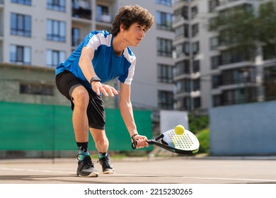 Sportive young boy with racquet playing padel in the open court outdoors - Powered by Shutterstock