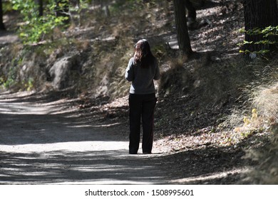 A sportive young woman in black sports clothing takes deep a breath after his exercise on a natural walkway nearby a lake in Berlin-Germany on a warm and sunny autumn day. - Powered by Shutterstock