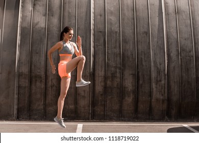 sportive young woman doing front knee lifts or running on the spot