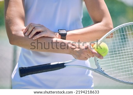 Sports, arm pain and tennis player with a racket and ball standing on a court during for a match. Closeup of a health, strong and professional athlete with equipment touching a medical elbow injury.