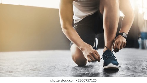 Sports, athlete and man tie shoes in a gym before workout for health, wellness and endurance training. Fitness, sneakers and closeup of male person tying laces to start a exercise in sport center. - Powered by Shutterstock