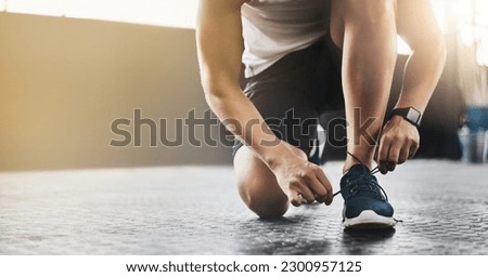 Sports, athlete and man tie shoes in a gym before workout for health, wellness and endurance training. Fitness, sneakers and closeup of male person tying laces to start a exercise in sport center.