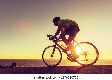 Sports Athlete Silhouette. Road Bike Cyclist Biking Near Ocean. Professional Triathlete Riding Bike On An Open Road To The Sunset. Active Healthy Man Sport Lifestyle.