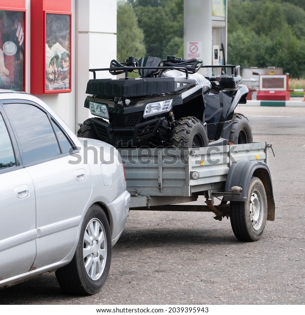 Sports ATV in a car trailer on a gas station in\
summer day