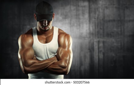 Sports Background. Bodybuilding. Strong Man  Posing On A Concrete Background