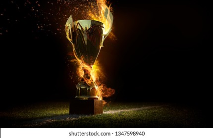Sports background. Burning trophy goblet. Winner in a competition. Fire and energy. Football field with golden goblet.