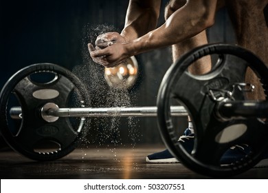 Sports background. Young athlete getting ready for weight lifting training. Powerlifter hand in talc preparing to bench press
