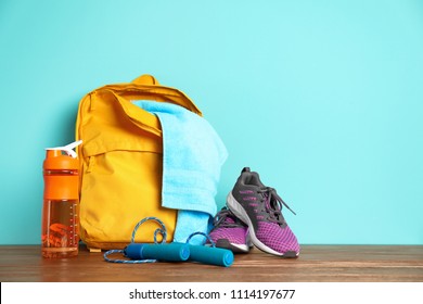 Sports Bag And Gym Equipment On Wooden Floor Against Color Background