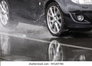 Sports car driven on rainy roads close up on a wheel with motion blur effect
