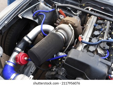 Sports Car Engine With Turbine. An Open Race Car Hood On A Pit Stop While Racing On A Race Track. Motor With Turbocharger. Boos And Tunning.