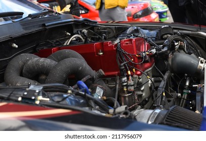 Sports Car Engine With Turbine. An Open Race Car Hood On A Pit Stop While Racing On A Race Track. Motor With Turbocharger. Boos And Tunning.