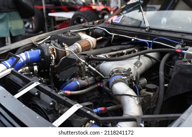 Sports Car Engine With Turbine. An Open Race Car Hood On A Pit Stop While Racing On A Race Track. Motor With Turbocharger. Boos And Tunning.