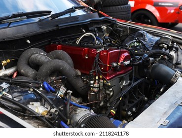 Sports Car Engine With Turbine. An Open Race Car Hood On A Pit Stop While Racing On A Race Track. Motor With Turbocharger. Boos And Tunning.