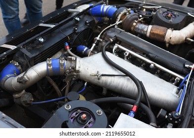 Sports Car Engine With Turbine. An Open Race Car Hood On A Pit Stop While Racing On A Race Track. Motor With Turbocharger. Boos And Tunning.