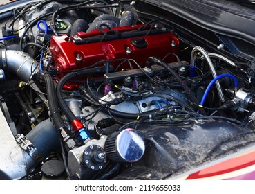 Sports Car Engine With Turbine. An Open Race Car Hood On A Pit Stop While Racing On A Race Track. Motor With Turbocharger. Boos And Tunning.