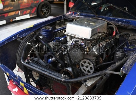 Sports car engine with turbine. An open race car hood on a pit stop while racing on a race track. Motor with turbocharger. Boos and tunning.