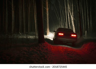 Sports Car With High Beam On In A Winter Pine Forest At Night, Front And Background Blurred With Bokeh Effect 