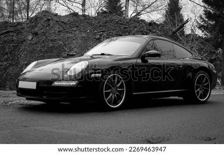 A sports car parked on the street against the background of a mound of earth.