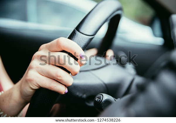 Sports car steering wheel, hands of a young girl with\
purple nai