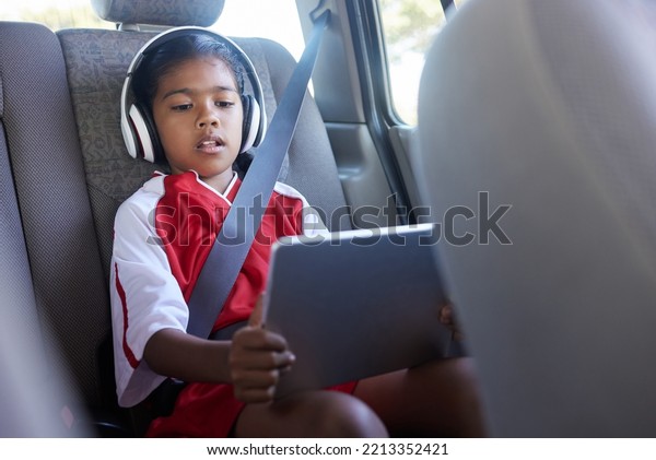 Sports, car travel and relax child with tablet on\
journey to soccer practice while streaming video, watch movie or\
play online games. Transport, SUV van or kid girl using tech before\
football match