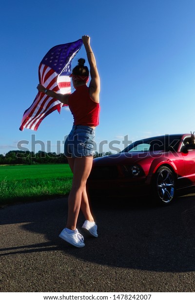 Sports cars at the start, speed and excitement. Top\
gear,Beautiful sexy blonde girl with a sports figure gives the\
go-ahead to cars with the American flag, attention to the start.\
Ready, set, go.
