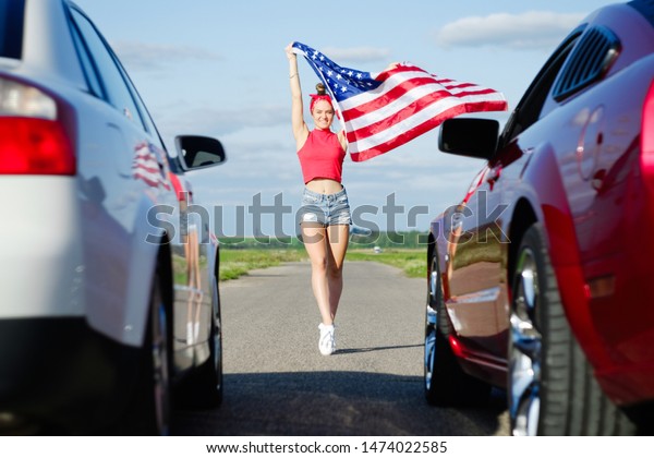 Sports cars\
at the start, speed and excitement,beautiful sexy blonde girl with\
a sports figure gives the go-ahead to cars with the American flag,\
attention to the start. Ready, set,\
go/