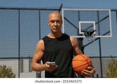 Sports caucasian man or basketball player using smartphone after outdoor training and looking at camera. Muscular athlete snacks on protein bar while resting after workout at stadium. - Powered by Shutterstock