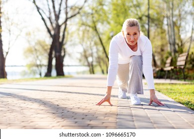 Sports competition. Pleasant aged woman starting to run while taking part in the competition