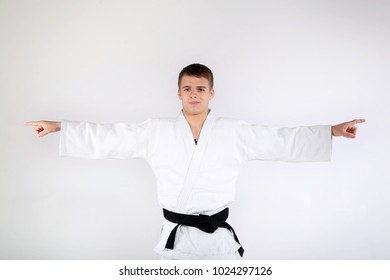 Sports concept. Judo, karate, black belt. A young man in a white kimono for sambo, judo. Portrait of a man karate in a white kimono in a fighting position, close-up. Black and light background