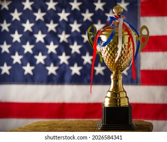 Sports Cup With Multicolored Ribbons And American Flag. Pride In Your Country, An Award To The Winner In Sports. There Are No People In The Photo. Advertising, Banner, Poster.