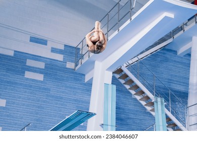 sports diving, an athlete doing a somersault, jumping from a springboard into the pool - Powered by Shutterstock