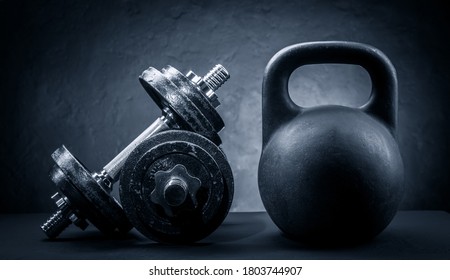 Sports dumbbells and kettlebell on a dark background - Powered by Shutterstock