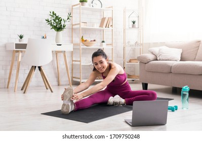 Sports During Lockdown. Attractive Woman Watching Online Training Class And Doing Stretching Exercises At Home