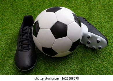 Sports Equipment, Athletics Competition And Sporting Event Concept With Soccer Ball, Leather Cleats Or Football Boots On Green Grass