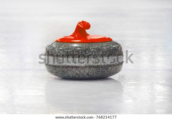 Sports equipment for Curling. Curling stones lined\
up on the playing field. Curling sports equipment, stone, red on\
the ice.