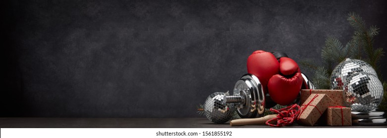 Sports Equipment: Dumbbell, Boxing Gloves, Skipping Rope, Fir Branch, Christmas Ornament, Gifts On Dark Grey Background With Copy Space. Fitness, Sport, Healthy Lifestyle Concept. New Year. Christmas