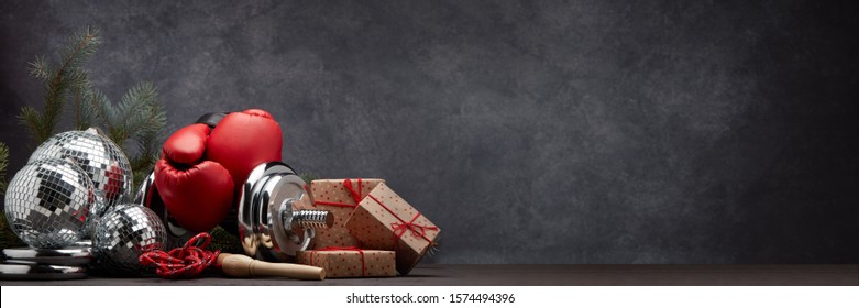 Sports Equipment: Dumbbell, Boxing Gloves, Skipping Rope, Fir Branch, Christmas Ornament, Gifts On Dark Grey Background With Copy Space. Fitness, Sport, Healthy Lifestyle Concept. New Year. Christmas