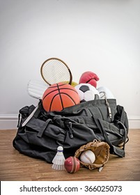 Sports Equipment In A Holdall Sports Bag On A Gym Floor. Football, Rugby, Baseball, Cricket, Basketball, Boxing, Badminton, Squash. Portrait With Copy Space.