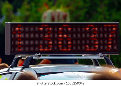 Sports event time counter displaying numbers of the running track. Set up on a car roof.