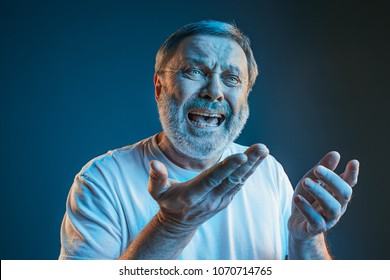 Sports, Fan Human Emotions And People Concept - Sad Senior Man Watching Sports On Tv And Supporting Team At Home. Crying Emotional Man Screaming In Colorful Bright Lights At Studio. Facial Expression